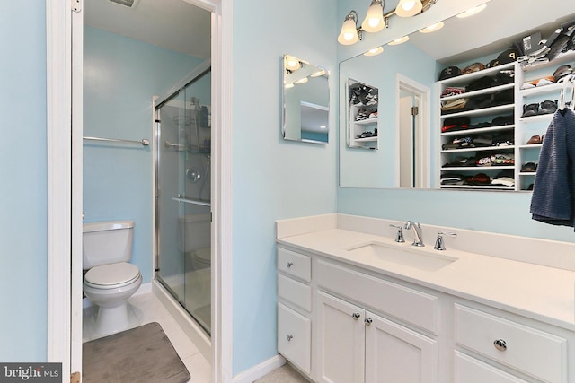 full bath with vanity, a walk in closet, toilet, and a shower stall