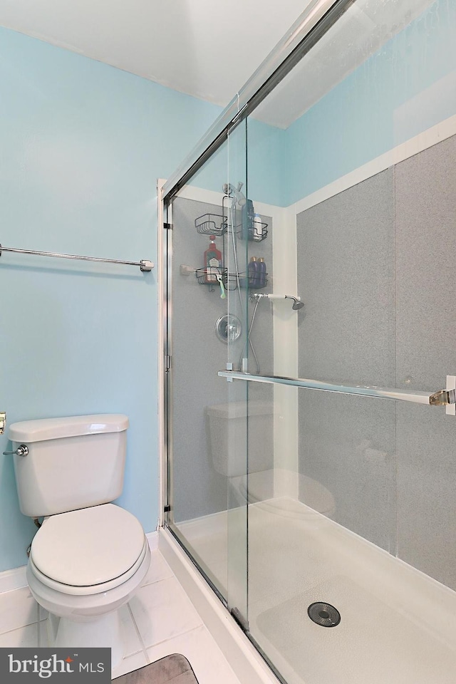 bathroom with tile patterned flooring, a shower stall, and toilet