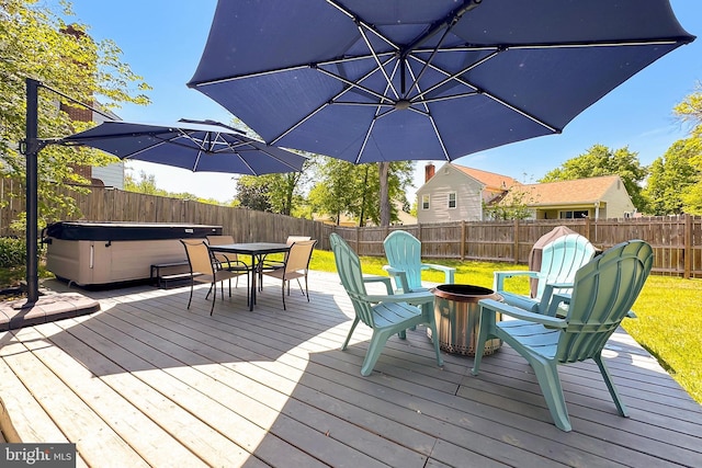 deck with a fenced backyard, a lawn, outdoor dining area, and a hot tub