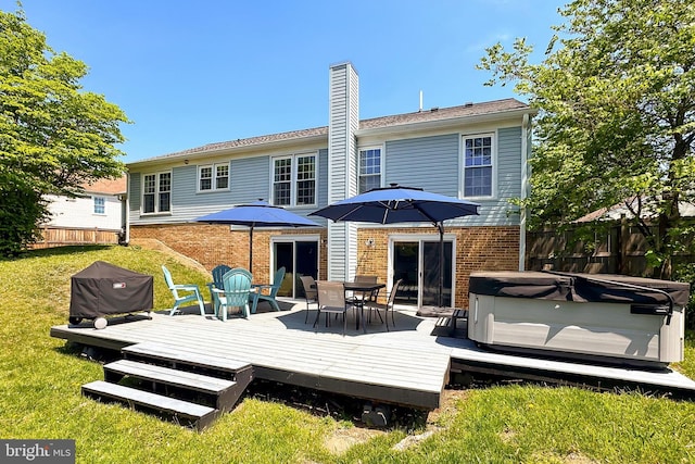 rear view of property with fence, a wooden deck, a chimney, and a hot tub