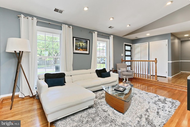 living room with visible vents, a wealth of natural light, vaulted ceiling, and wood finished floors