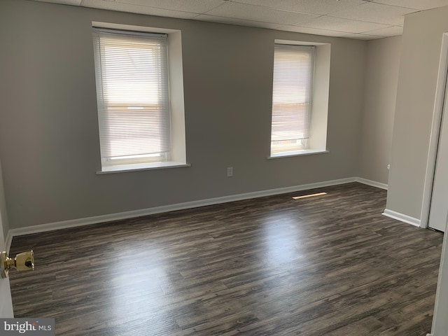 spare room with a healthy amount of sunlight, dark wood-type flooring, and a paneled ceiling