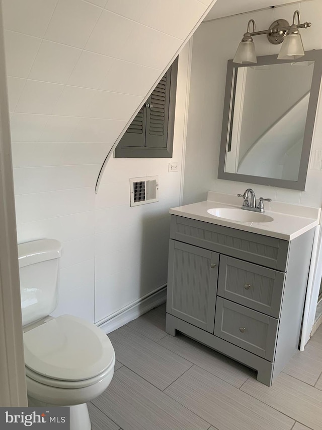 half bath with visible vents, vanity, and toilet