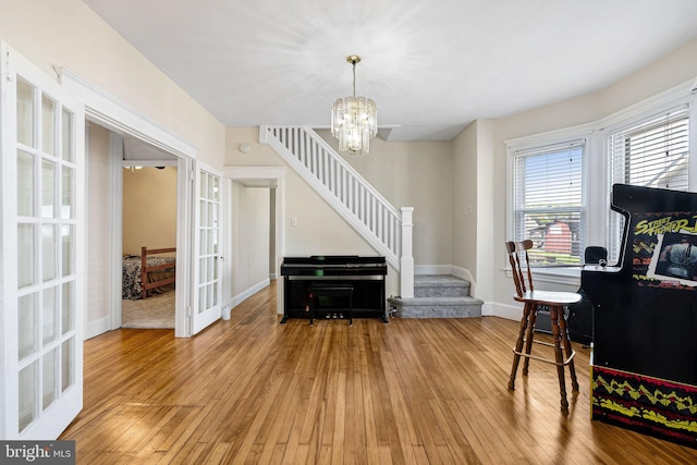 interior space featuring french doors, stairway, baseboards, an inviting chandelier, and hardwood / wood-style floors
