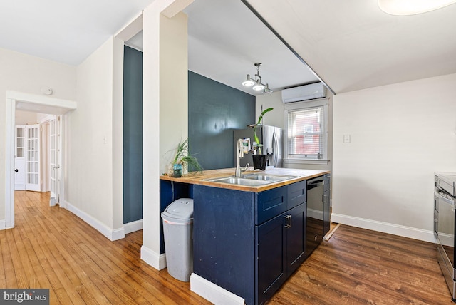 kitchen featuring blue cabinetry, appliances with stainless steel finishes, a wall unit AC, and hardwood / wood-style floors