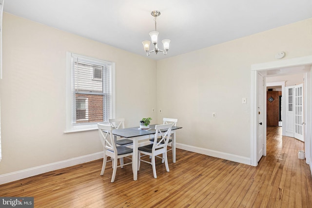 dining area featuring an inviting chandelier, baseboards, and light wood-type flooring