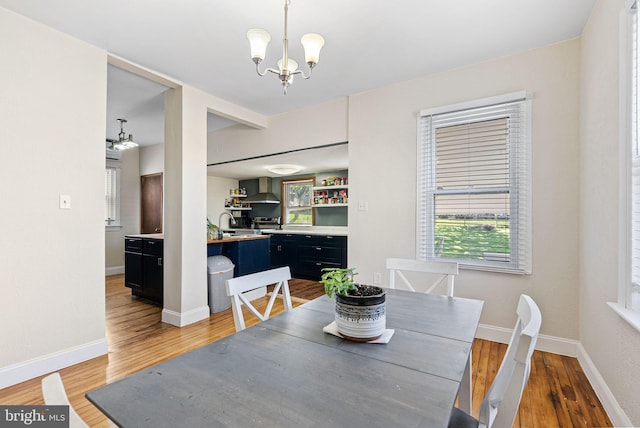 dining area featuring baseboards, a chandelier, and light wood-style flooring