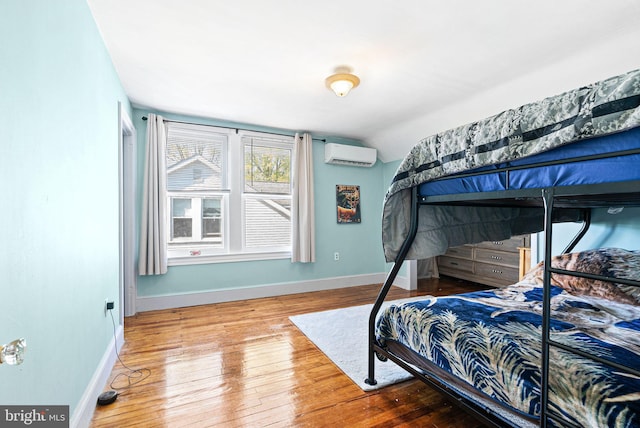 bedroom with baseboards, a wall mounted air conditioner, lofted ceiling, and wood finished floors