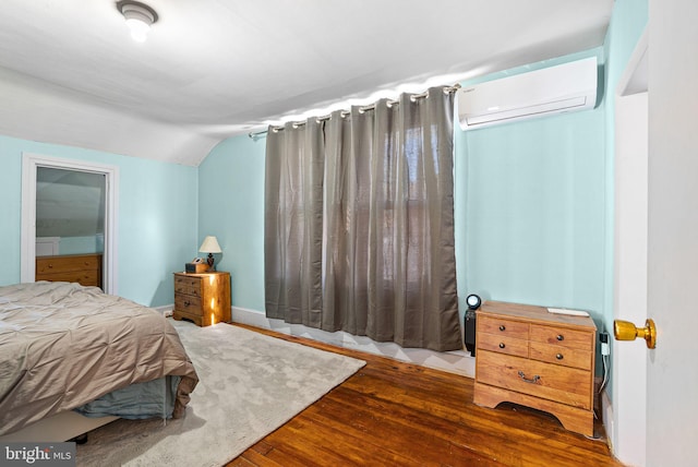 bedroom with an AC wall unit, wood finished floors, and vaulted ceiling