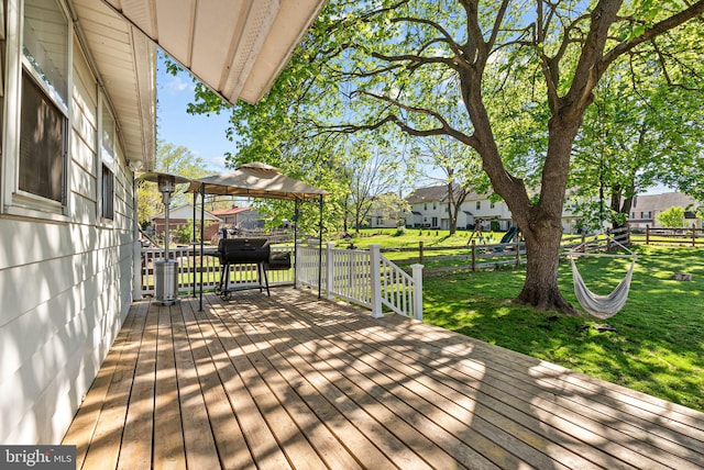 wooden deck with a lawn, fence, a gazebo, and area for grilling