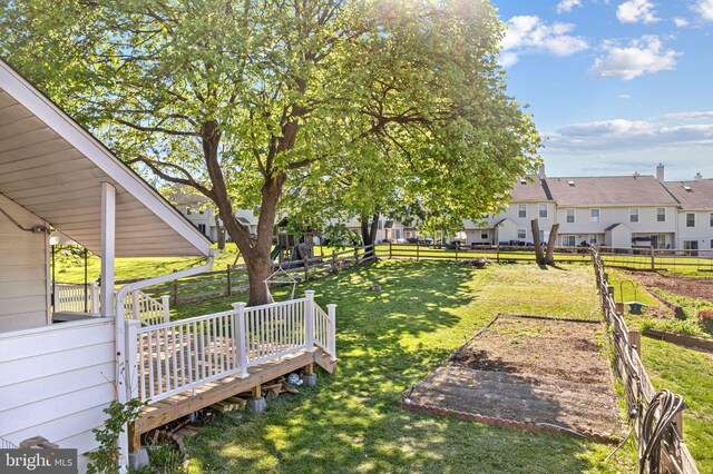 view of yard featuring a residential view, fence, a vegetable garden, and a deck
