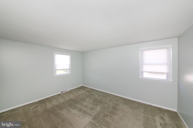 carpeted empty room with plenty of natural light, baseboards, and visible vents