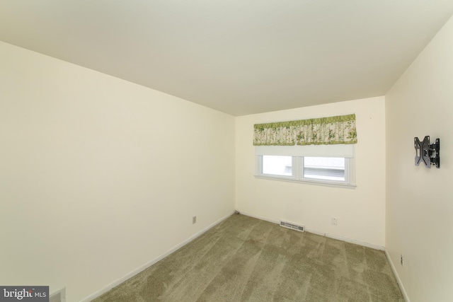spare room featuring baseboards, visible vents, and light carpet