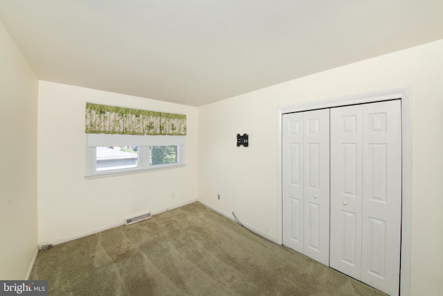 unfurnished bedroom with carpet flooring, visible vents, and a closet