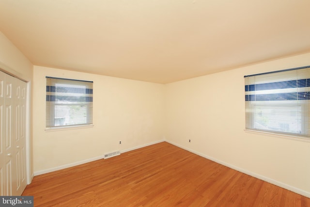 unfurnished bedroom with baseboards, a closet, light wood finished floors, and visible vents