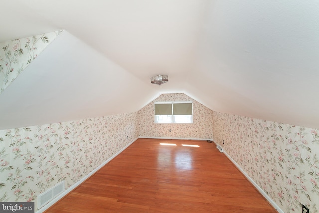 bonus room featuring visible vents, wood finished floors, and wallpapered walls