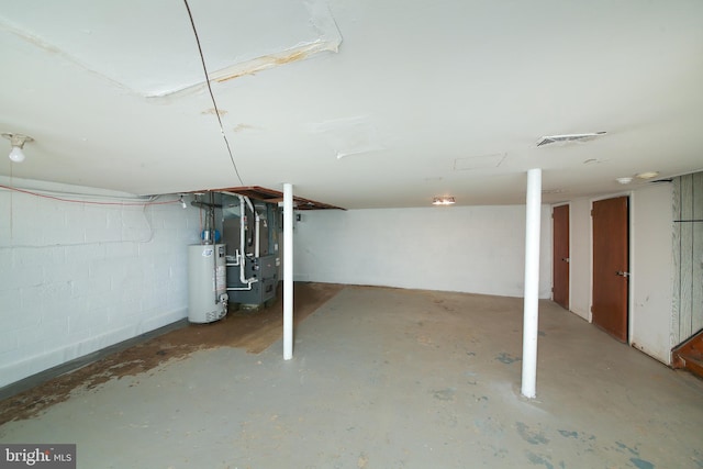 unfinished below grade area with heating unit, concrete block wall, gas water heater, and visible vents