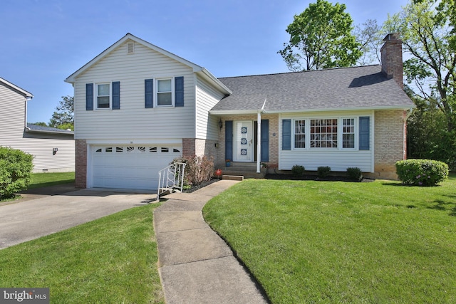 tri-level home featuring driveway, a chimney, a front yard, a garage, and brick siding