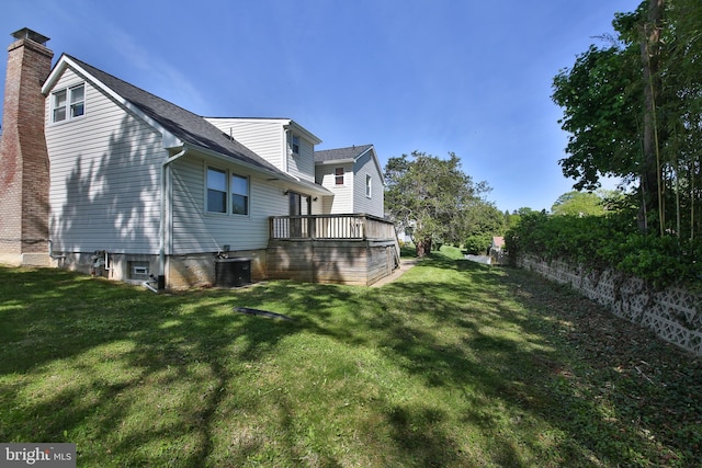 view of home's exterior featuring a deck, cooling unit, a chimney, a shingled roof, and a lawn