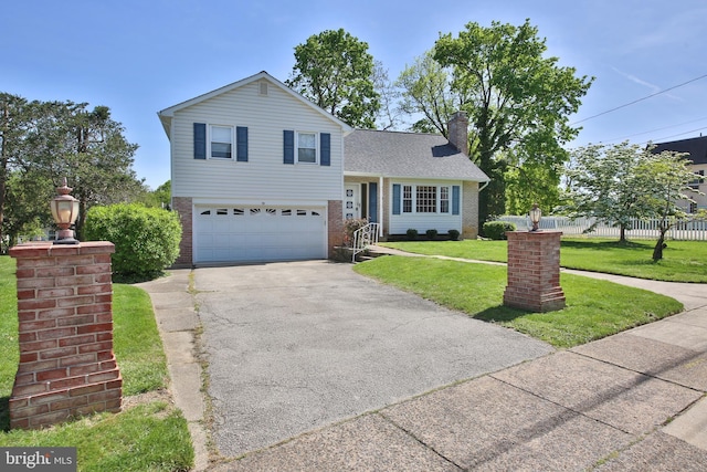 tri-level home featuring aphalt driveway, brick siding, fence, a front lawn, and an attached garage