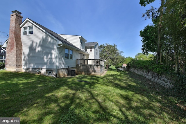 view of side of property with a yard, a deck, a chimney, and central AC unit