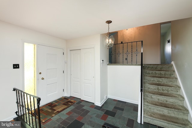 foyer featuring stairway, baseboards, and a chandelier