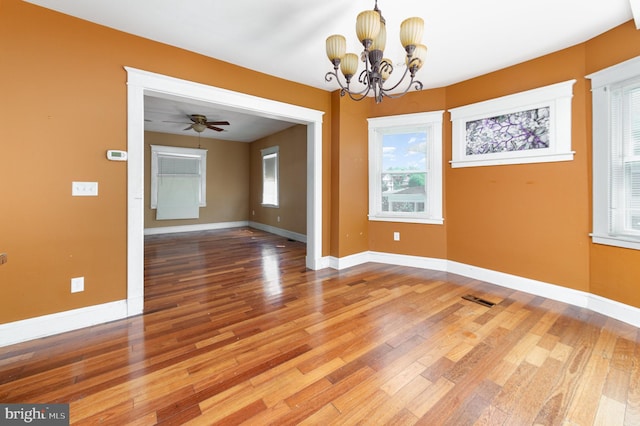 unfurnished dining area featuring baseboards, visible vents, wood finished floors, and ceiling fan with notable chandelier