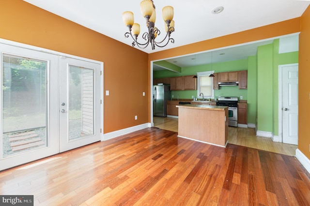 kitchen with a notable chandelier, appliances with stainless steel finishes, french doors, light wood-style flooring, and baseboards