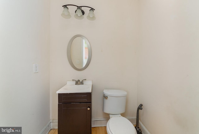 half bath featuring vanity, baseboards, and toilet