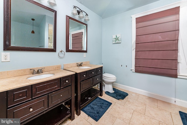 bathroom featuring a sink, baseboards, toilet, and two vanities