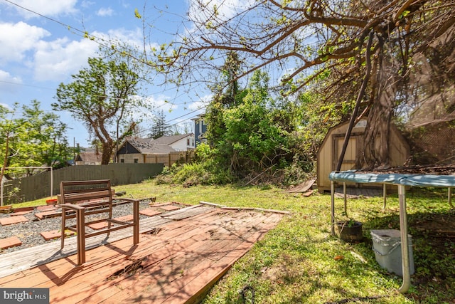 view of yard featuring a fenced backyard, a trampoline, and a wooden deck