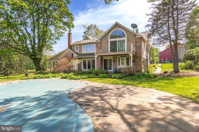 view of front of home featuring brick siding, a chimney, and a front yard
