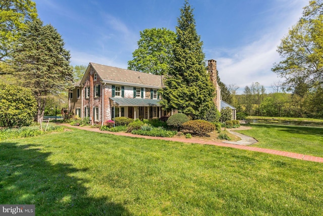 view of front of home with brick siding, a chimney, and a front lawn