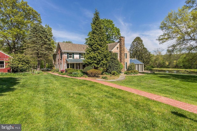 view of front of property with a water view, a chimney, and a front yard