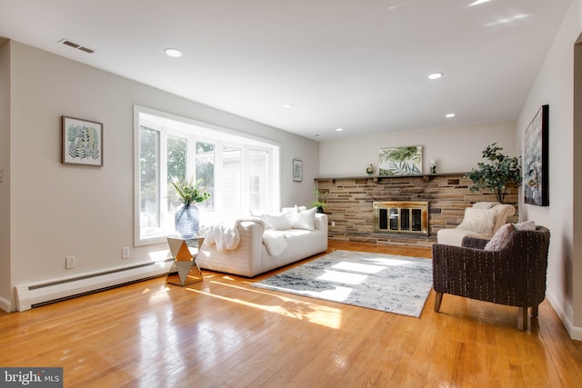 living area with a stone fireplace, visible vents, wood finished floors, a baseboard radiator, and recessed lighting