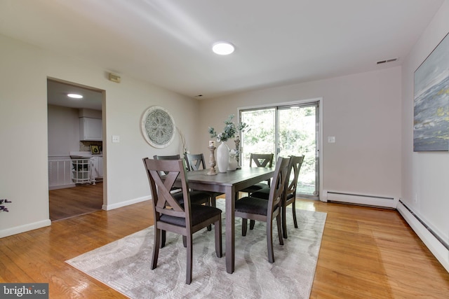 dining room with light wood-style floors, visible vents, baseboards, and a baseboard radiator
