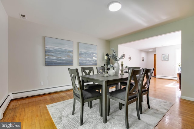 dining space featuring visible vents, a baseboard radiator, light wood finished floors, and a baseboard heating unit