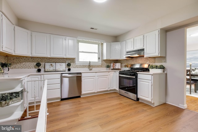 kitchen with stainless steel dishwasher, under cabinet range hood, gas range oven, and decorative backsplash