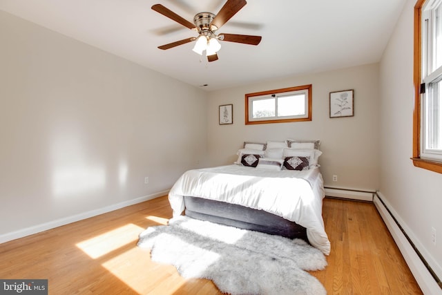 bedroom with baseboards, a baseboard radiator, a ceiling fan, and light wood-style flooring