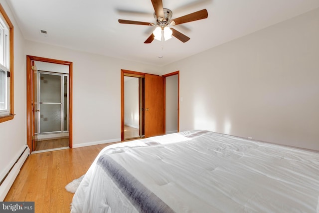 bedroom featuring visible vents, baseboard heating, baseboards, a closet, and light wood-style flooring