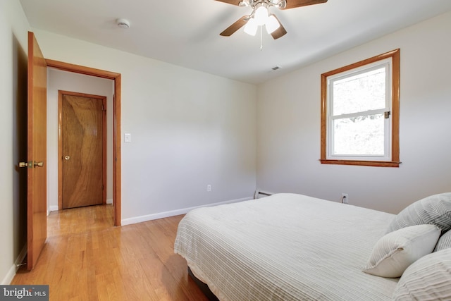 bedroom featuring light wood-style floors, a ceiling fan, baseboards, and visible vents