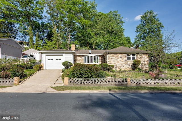 ranch-style home featuring a garage, a chimney, concrete driveway, and stone siding