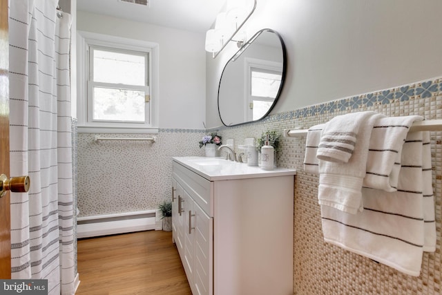 bathroom featuring visible vents, wainscoting, wood finished floors, vanity, and a baseboard radiator