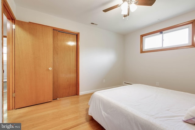 bedroom with visible vents, light wood-style flooring, baseboards, a baseboard heating unit, and a closet