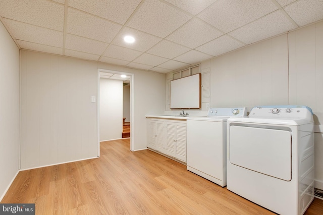 washroom featuring light wood-style floors, washing machine and dryer, and cabinet space
