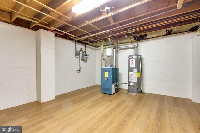 unfinished below grade area featuring concrete block wall, a heating unit, wood finished floors, and water heater