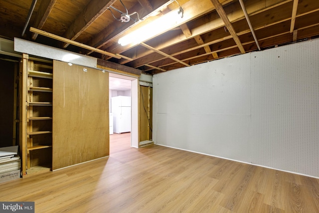 unfinished below grade area with freestanding refrigerator and wood finished floors