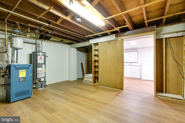 unfinished below grade area featuring washer / dryer, gas water heater, wood finished floors, and a heating unit