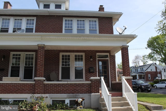 american foursquare style home with brick siding and a chimney