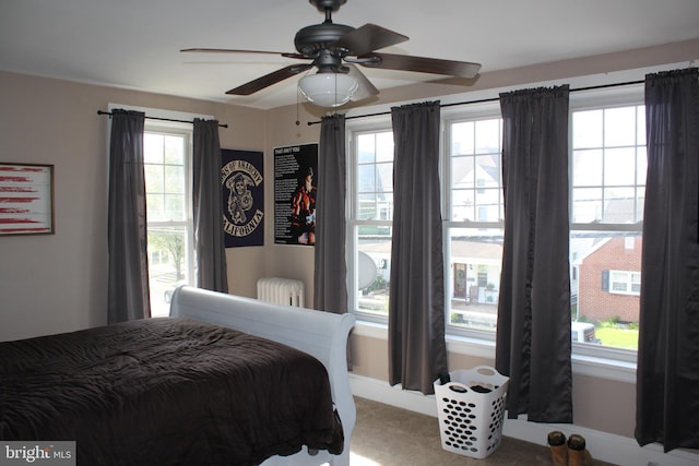 carpeted bedroom featuring radiator, multiple windows, and a ceiling fan
